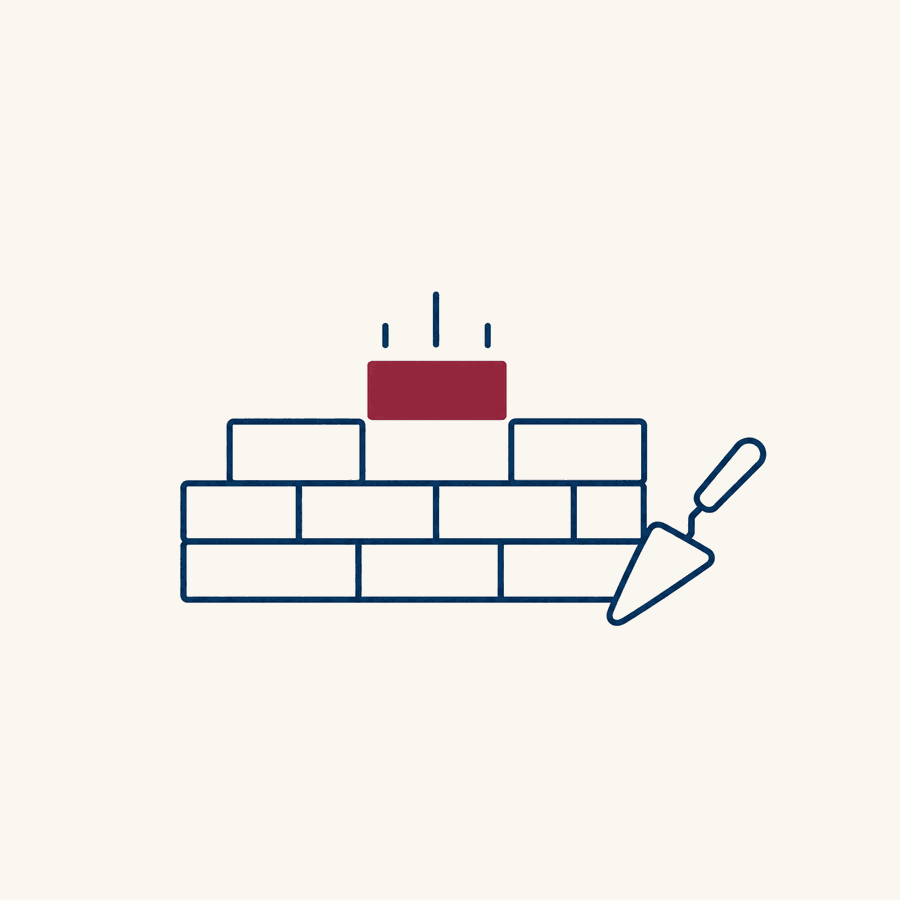 A short wall of navy outlined bricks in three rows with a trowel leaning against it, and one burgundy brick being lowered into the gap on top